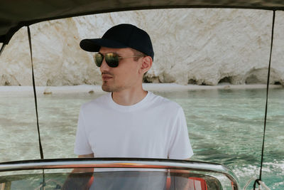 A young guy controls a boat on the sea.