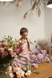 Beautiful woman making bouquet on table