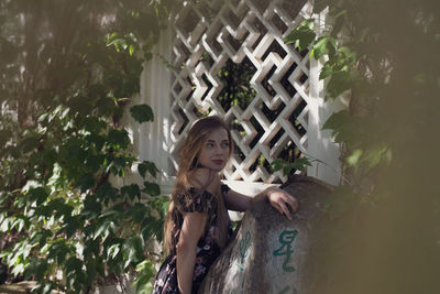 Portrait of woman standing against plants