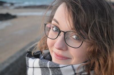 Portrait of smiling young woman wearing eyeglasses at beach