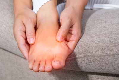 Cropped hands of person holding swollen feet