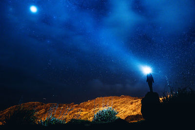 Rear view of silhouette man standing against sky at night