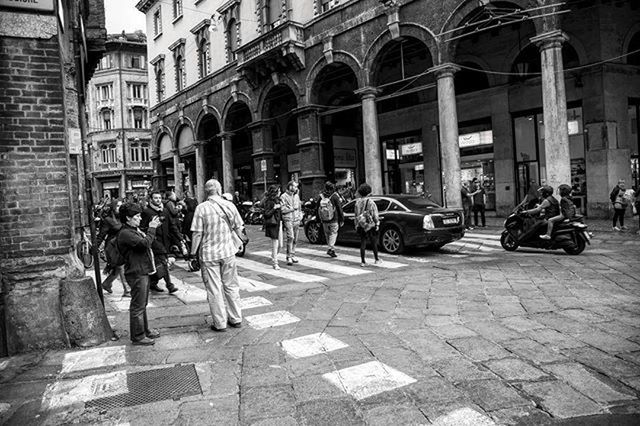 building exterior, architecture, men, large group of people, built structure, person, street, city, lifestyles, city life, walking, leisure activity, city street, mixed age range, cobblestone, transportation, full length, medium group of people, town square