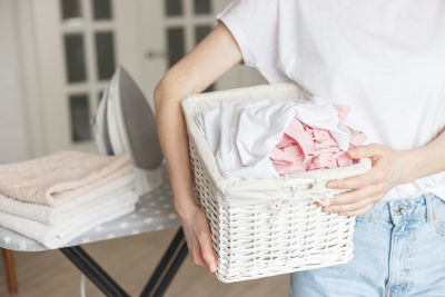 Midsection of woman sitting in basket at home