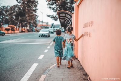 Rear view of people walking on zebra crossing in city