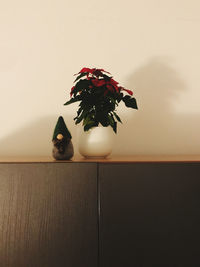 Flower vase on table against wall