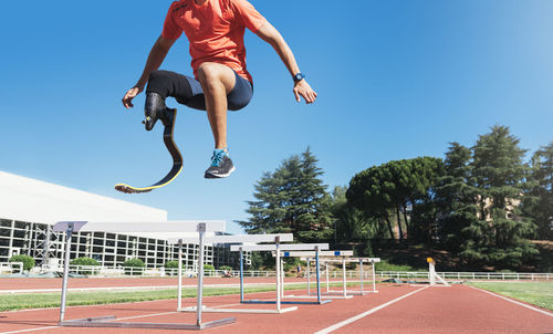 Low section of athlete with prosthetic leg jumping on sports track