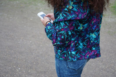 Midsection of woman using mobile phone while standing on street