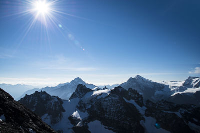 Scenic view of snowcapped mountains during sunny day