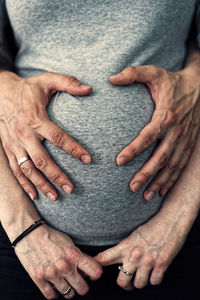 Cropped image of man with hands of pregnant woman belly