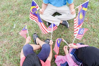 People with malaysian flags sitting on field