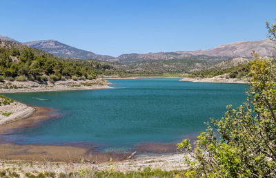 Scenic view of sea and mountains against clear blue sky