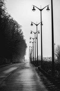 Road amidst bare trees against clear sky