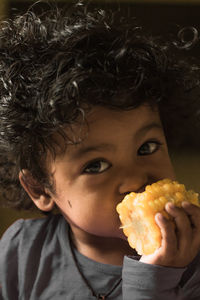 Close-up portrait of boy eating corn