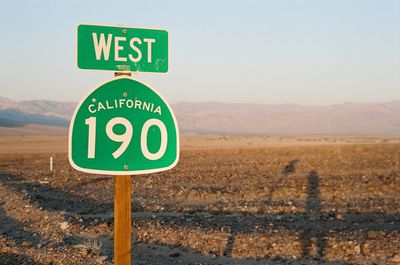 Road sign on field against clear sky