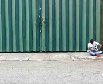Full length of man sitting on wall