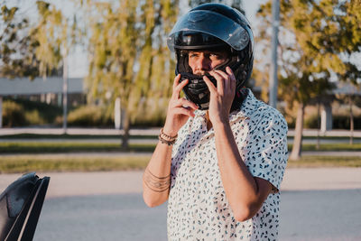 Young male with hipster outfit put the motorbike helmet in. he is a caucasian good looking male 