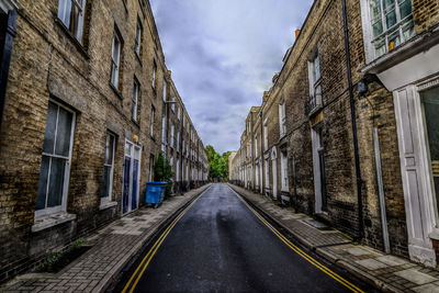 Empty road amidst buildings in city