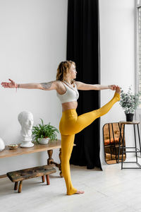 Full length of woman standing on potted plant at home