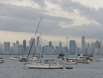 Sailboats in sea against buildings in city