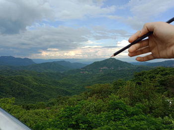 Person holding pencil against mountains
