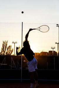 Silhouette man playing with ball in background