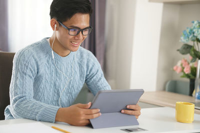 Young man using mobile phone while sitting on table