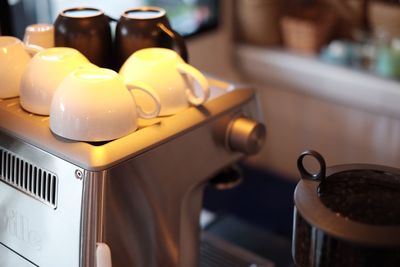 Close-up of cups on espresso machine in cafe