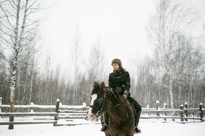 Beautiful woman riding horse on snow covered field