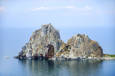 Rocky cliff on sea against sky