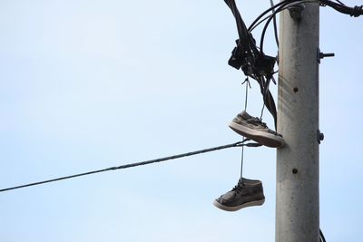 Low angle view of shoes hanging against clear sky