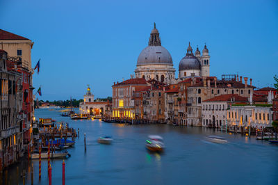 Boats moored in canal by buildings against sky in city