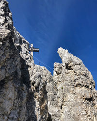 Low angle view of rocky mountain against blue sky