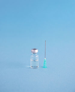 Close-up of needle and bottle on blue background
