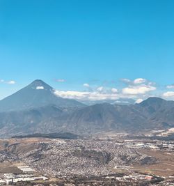 Aerial view of snowcapped mountains against blue sky