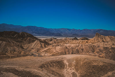 Scenic view of arid landscape against clear blue sky