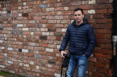 Portrait of a young man standing against brick wall