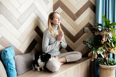 Full length of woman with dog meditating at home