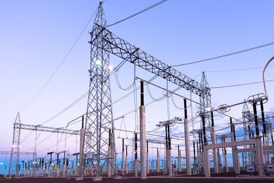 Low angle view of electricity pylons against clear sky