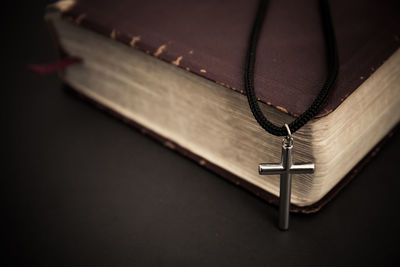 A cross with holy bible on a dark background. 