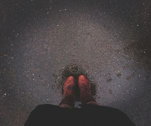 Low section of man wearing shoes standing on wet street