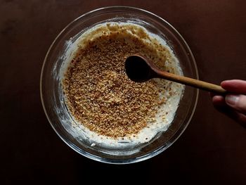 Human hand holding wooden spoon against bowl 