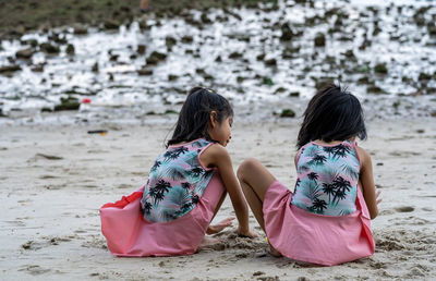 Rear view of women sitting on beach