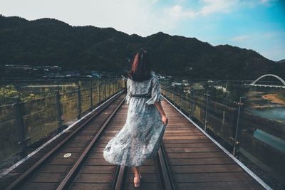 Rear view of woman standing on bridge against sky