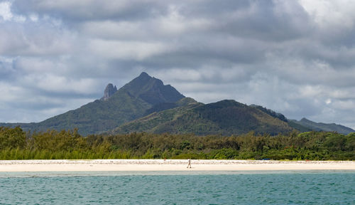 Scenic view of sea by mountains against sky