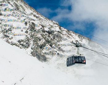 Overhead cable car on snow covered mountain against sky