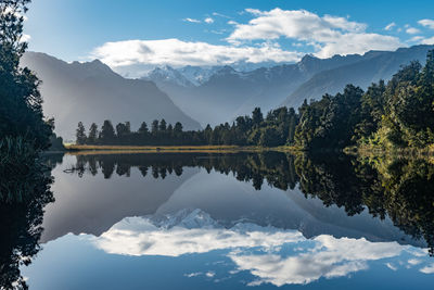 Scenic view of lake and mountains against sky with reflections at lake matheson, new zealand