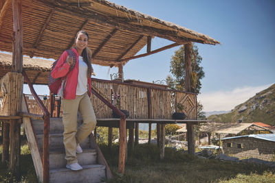 Young tourist comes out of a wooden cabin with a view of the mountain. hiking concept