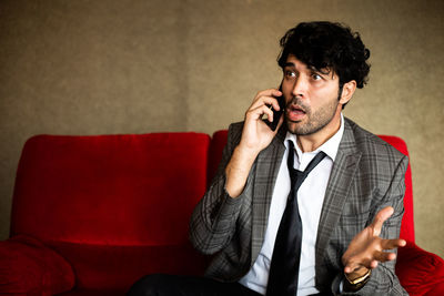 Young man using mobile phone while sitting on sofa