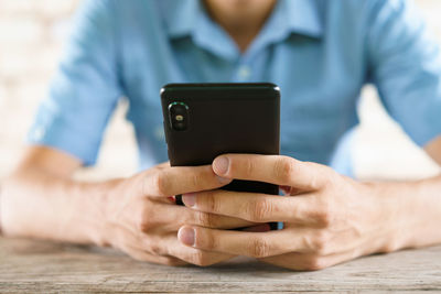 Midsection of man using mobile phone on table